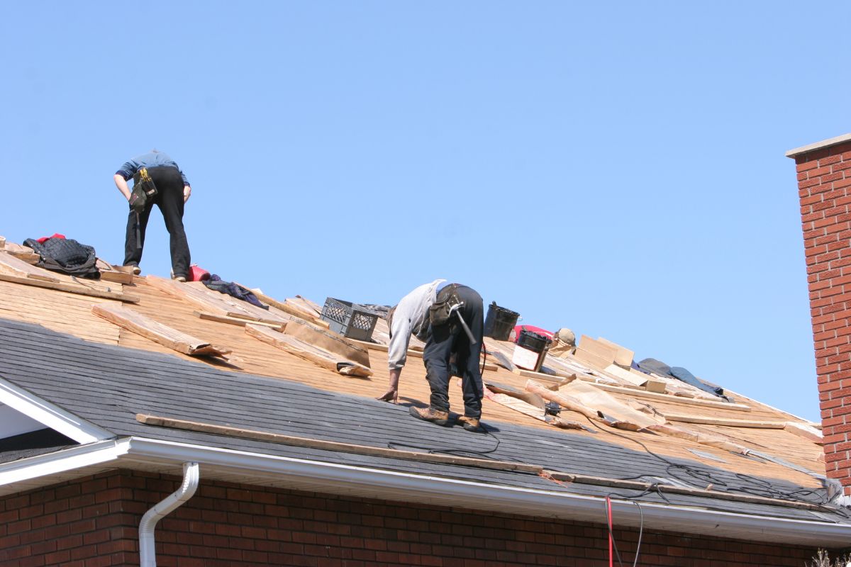 Three men are performing roofing tasks.